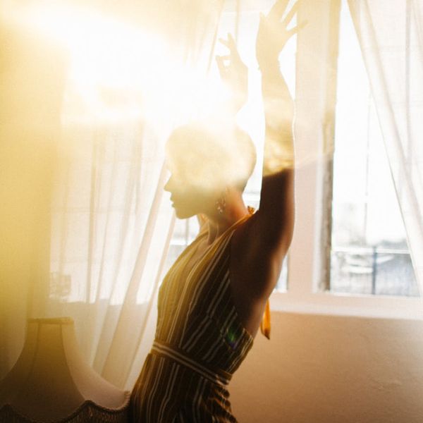 A woman meditating peacefully by a window with soft light.